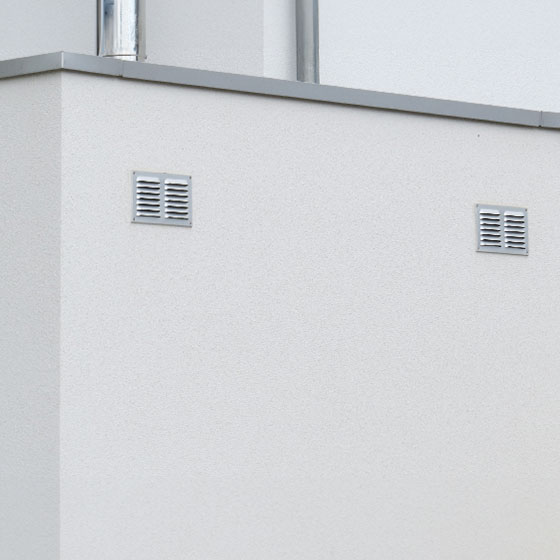 Blog: Pluspunkt bei Minusgraden. Das Bild zeigt eine weiße Garage von hinten, an deren Mauer sich zwei Lüftungsschächte befinden. Diese Details betonen die funktionale und durchdachte Konstruktion der Garage, die nicht nur ästhetisch, sondern auch praktisch gestaltet ist.
