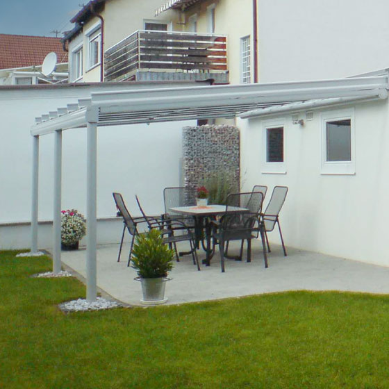 Erweiterung für Freisitz - Einladende, überdachte Terrasse mit an der Hauswand befestigter Pergola.