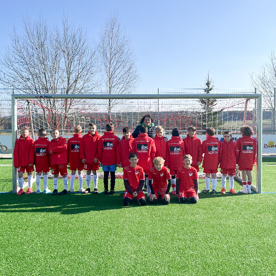 IBK engagiert sich für die Region. Das Bild zeigt eine Fußballmannschaft mit kleinen Jungen, die alle das neueste Trikot mit dem Logo von IBK Villingen auf dem Rücken tragen. Sie stehen gemeinsam im Tor, und Frau Scharp befindet sich in der Mitte.